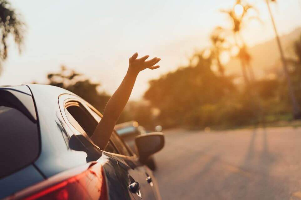 woman summer vacation in blue car at sunset