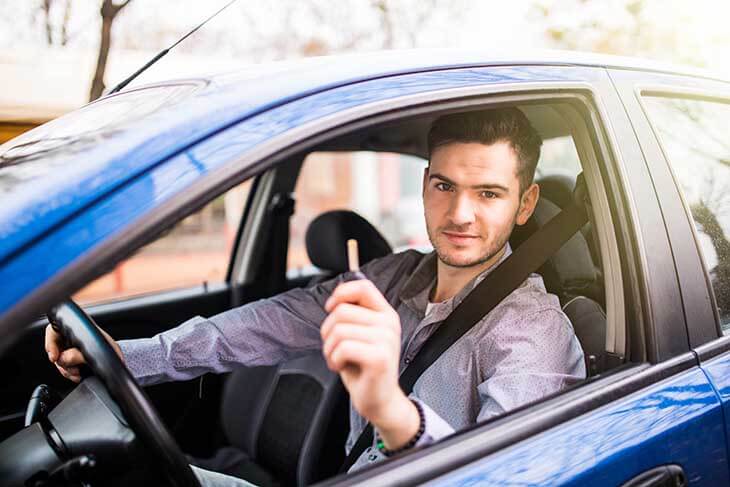 Young man driving his new car, holding out keys