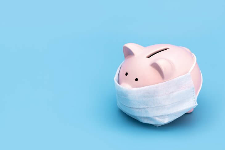 Pink piggy Bank stands on a blue medical background in a medical mask,, 