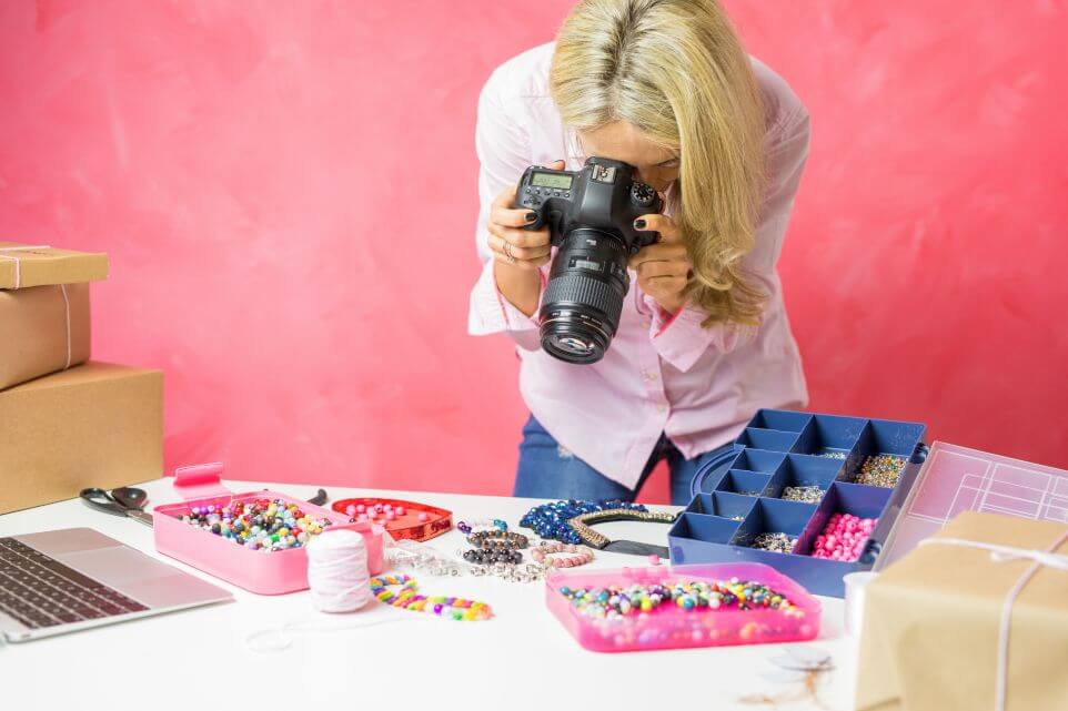 Woman taking photos of her own created merchandise, sells them online and mails packages to buyers.
